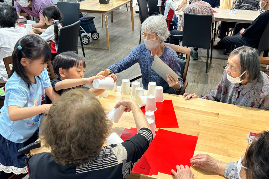 Nursery school children in Japan playing a building game with senior sitizens at Azalee Group's A-Cube