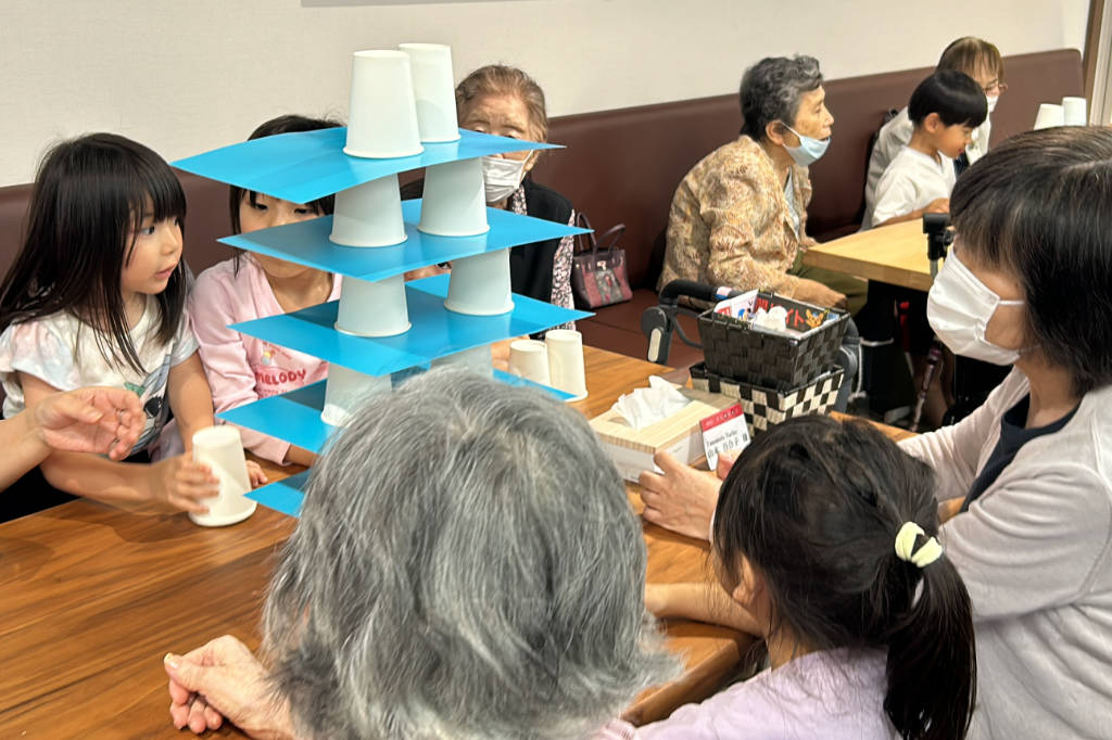 Nursery school children in Japan playing a building game with senior sitizens at Azalee Group's A-Cube