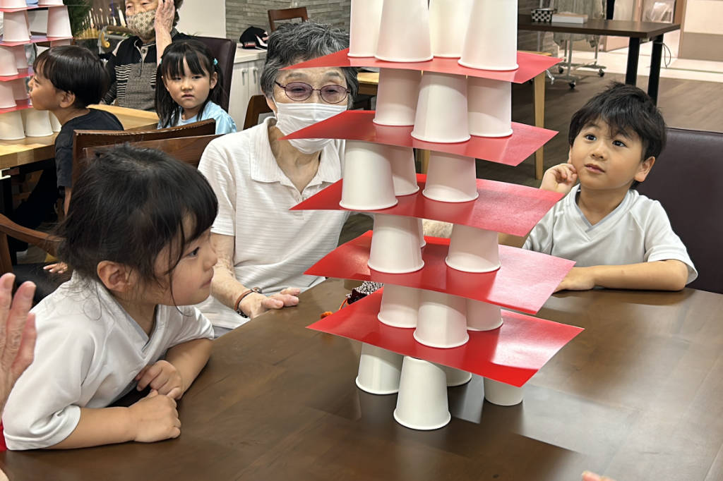 Nursery school children in Japan playing a building game with senior sitizens at Azalee Group's A-Cube