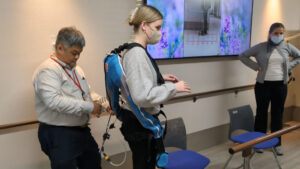 A staff member of Azalee Group adjusts a wearable muscle suit on a masked woman at Azalee Group's A-Cube facility.